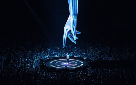 M Pokora se produit sur une scène circulaire au centre de l'arène, entouré de milliers de spectateurs. Au-dessus de lui, une main géante, ajoutant une touche futuriste à la scénographie de son Epicentre Tour.