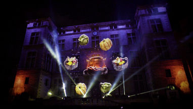 Projection de morceaux d'horloge flottant dans les airs, symbolisant le temps brisé, tandis qu'une luciole lumineuse se révèle pour guider les spectateurs.