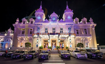 Façade extérieure de l’Hôtel de Paris à Monaco, illuminée pour la célébration, avec plusieurs voitures de luxe garées à l’entrée, mettant en avant l’élégance de l’événement.