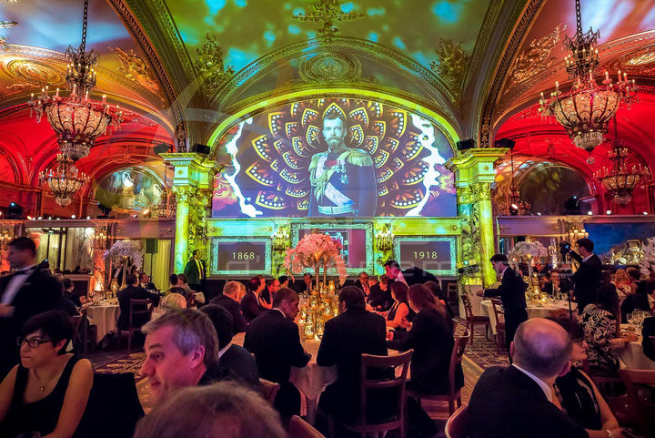 Scène de la salle de réception avec des projections artistiques de portraits historiques et des éléments de décoration rappelant la Russie impériale, offrant une atmosphère théâtrale et immersive aux convives.