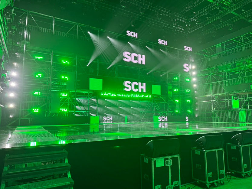 Une autre vue de la scène montre un ensemble d'écrans LED verts avec le logo "SCH" en préparation pour une performance. Studio ENORME a travaillé en étroite collaboration avec Black Dynamite pour synchroniser parfaitement les visuels avec la mise en scène et la scénographie.