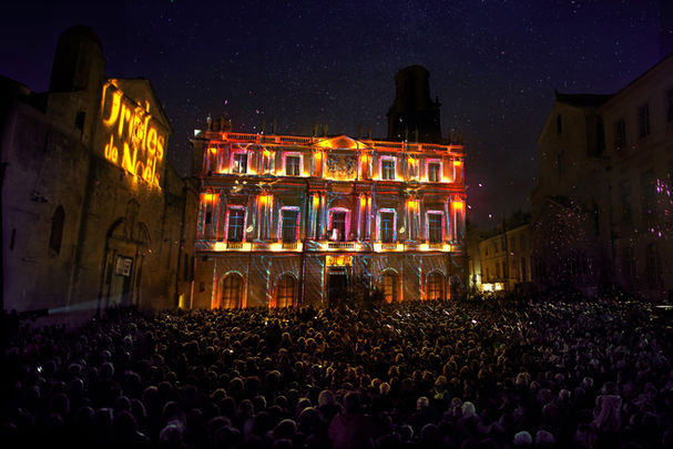 Vue de la foule assistant à un jeu de lumières éclatantes et multicolores sur la mairie pour célébrer Noël.