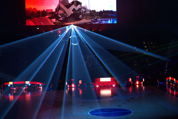 Un jeu de lumière laser illumine le terrain, avec des faisceaux convergeant vers le centre, accentuant l'effet dramatique et immersif de l’événement.