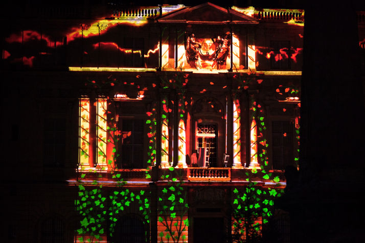 Motifs de feuilles et de branches en projection, transformant la mairie en une scène naturelle et poétique.