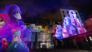 Projection de mapping au CHU de Nice, mettant en lumière des silhouettes colorées de personnel médical en tenue de protection, intégrées dans un décor urbain moderne et illuminées par des effets visuels vibrants.