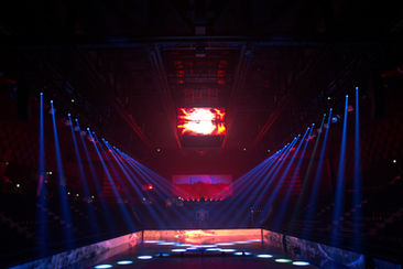 Vue de la salle avec des lumières rouges et bleues convergeant vers la scène, créant une ambiance spectaculaire lors de la projection des contenus visuels sur les écrans géants.