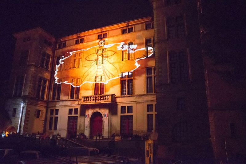 Le château illuminé par une projection d'engrenages, symbolisant le mécanisme du temps arrêté à Éguilles.