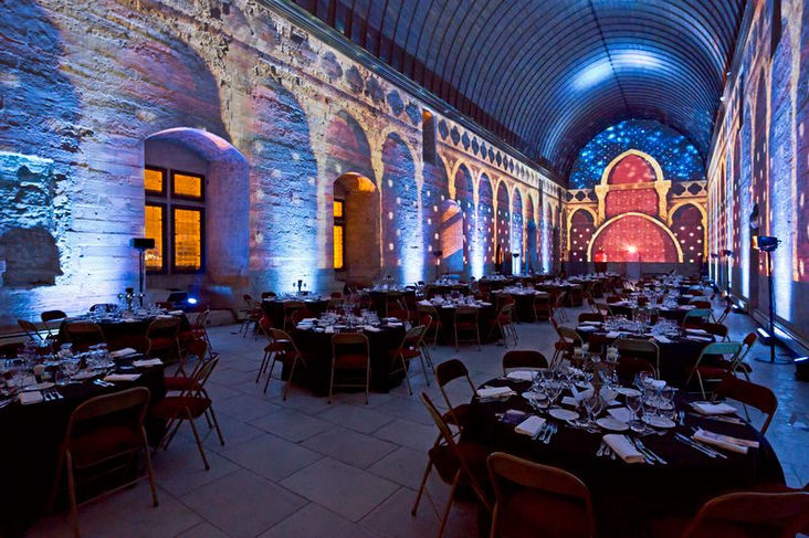 Vue de la salle du Grand Tinel, transformée en espace immersif avec des projections lumineuses, recréant des détails architecturaux et historiques sur les murs de pierre.