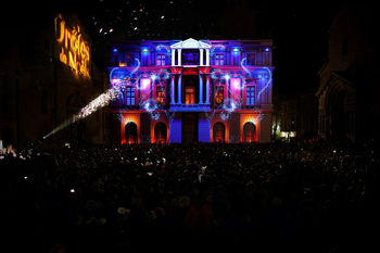 Une foule de spectateurs assiste à la projection de « L’Odyssée Givrée » sur un bâtiment. Les animations mettent en lumière un Noël magique et inattendu, rempli de surprises visuelles.