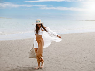 woman summer style walking on beach sunlight hat