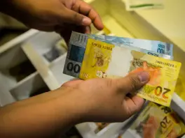 Mãos segurando uma nota de 20 e 100 reais
