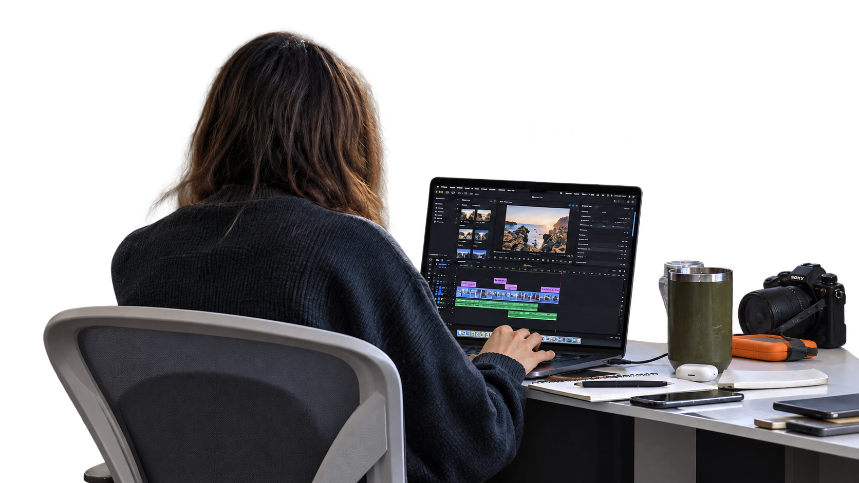 An editor at a laptop, with a chair, desk and filming equipment.