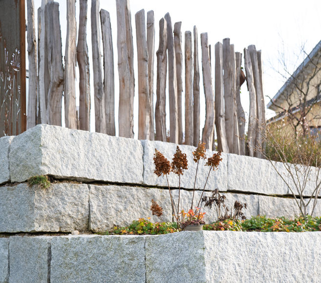 Sitzplatzerweiterung aufgefangen durch eine abgestufte Granitmauer. Umgestaltung Gartenanlage - PRIMA Gartenbau Reinach