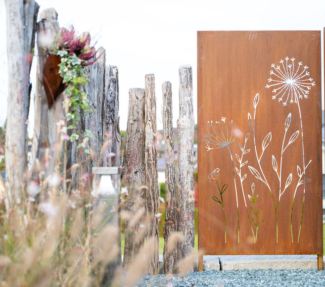 Sitzplatzerweiterung aufgefangen durch eine abgestufte Granitmauer,
Kiesbelag und einer Feuerstelle in Kombination mit einem Holzdeck und
Natursteinbelägen