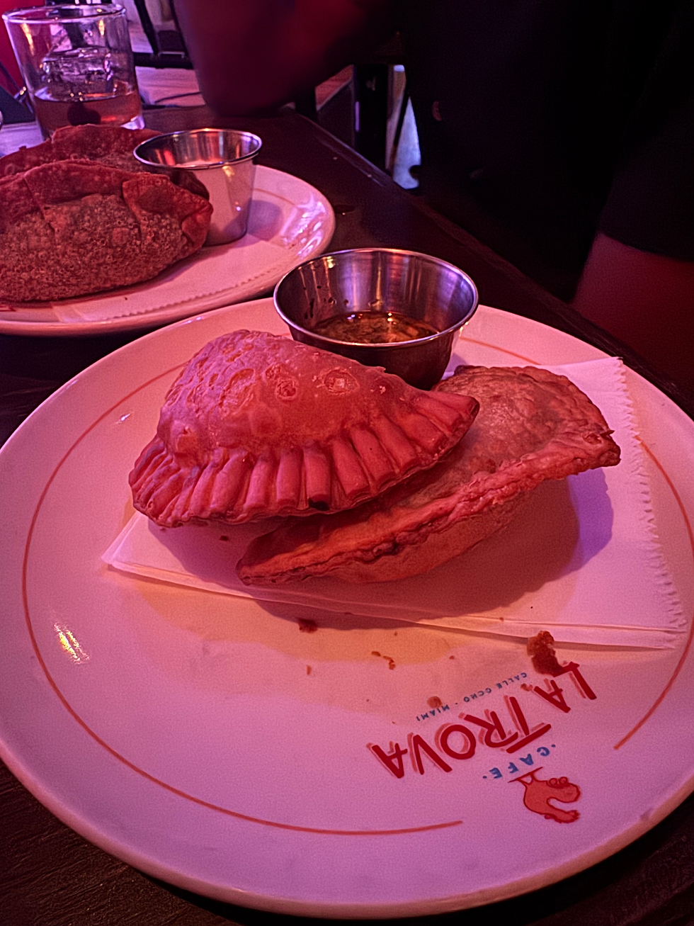 dishes of chicken empanadas in the forefront and spinach empanadas behind