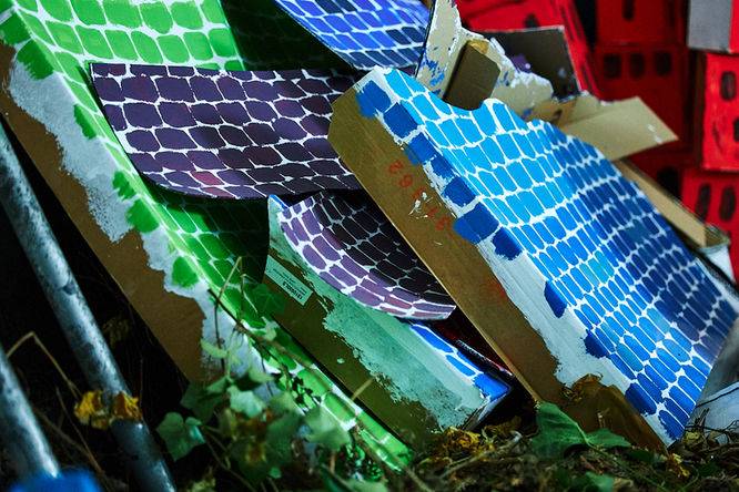 Als Mauer bemalte Pappkartons lehnen an einer Wand.