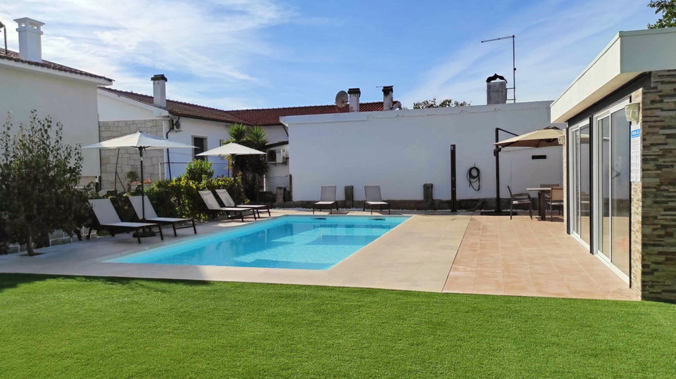 Piscina com espreguiçadeiras guarda-sol e relvado