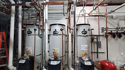 three commercial water heaters in a mechanical room