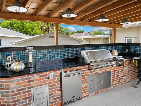 Outdoor kitchen with brick, blue tile backsplash, and grill