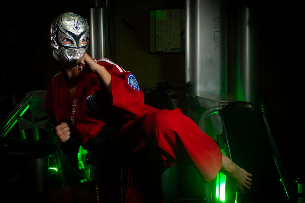 Hermosa modelo alta vestida en traje de karate importando una máscara de luchadora de típicas luchas mexicanas esta imagen es