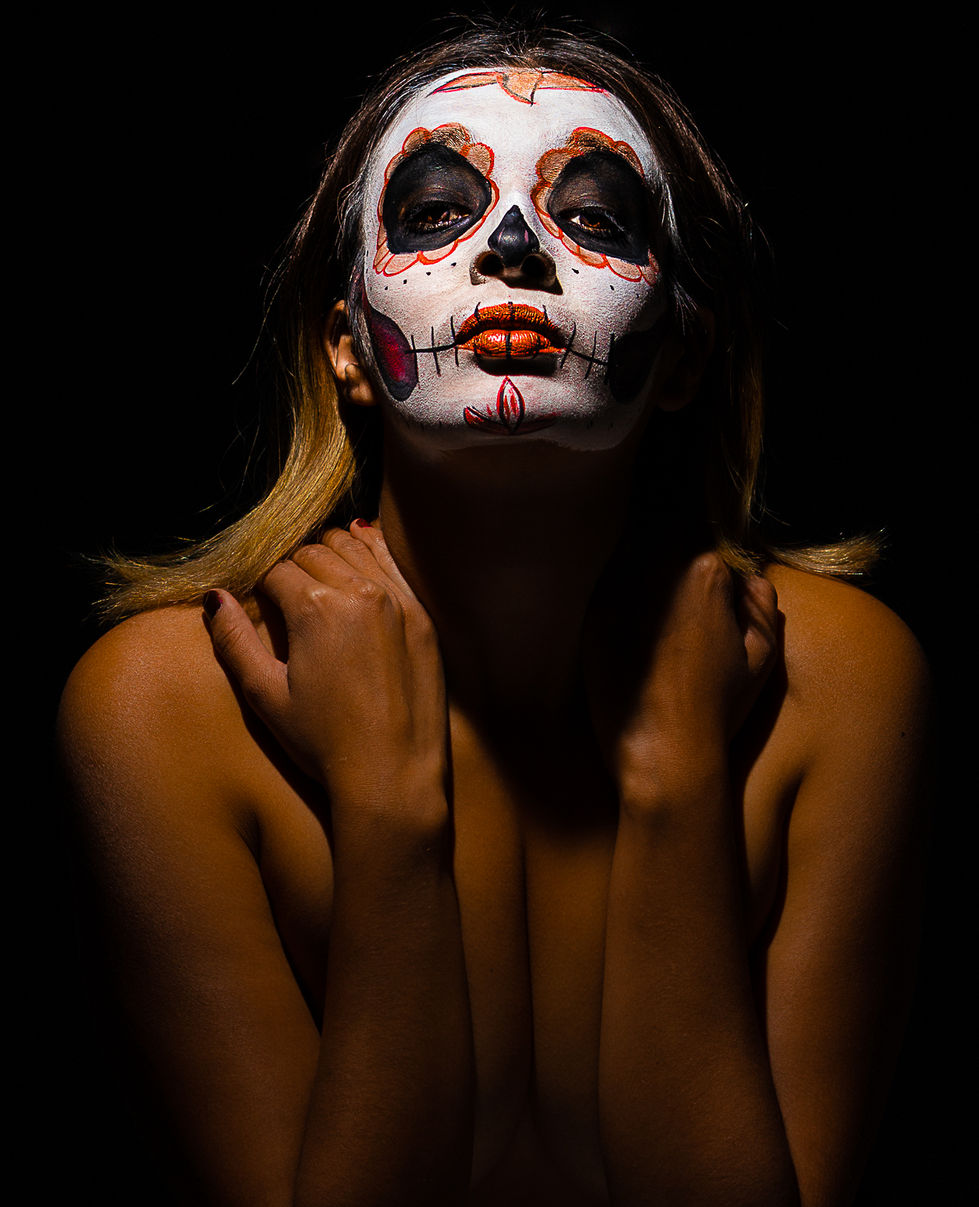 Modelo desnuda que se sostiene el cuello de manera que no muestra ninguna parte íntima su cara está pintada como Catrina y ti