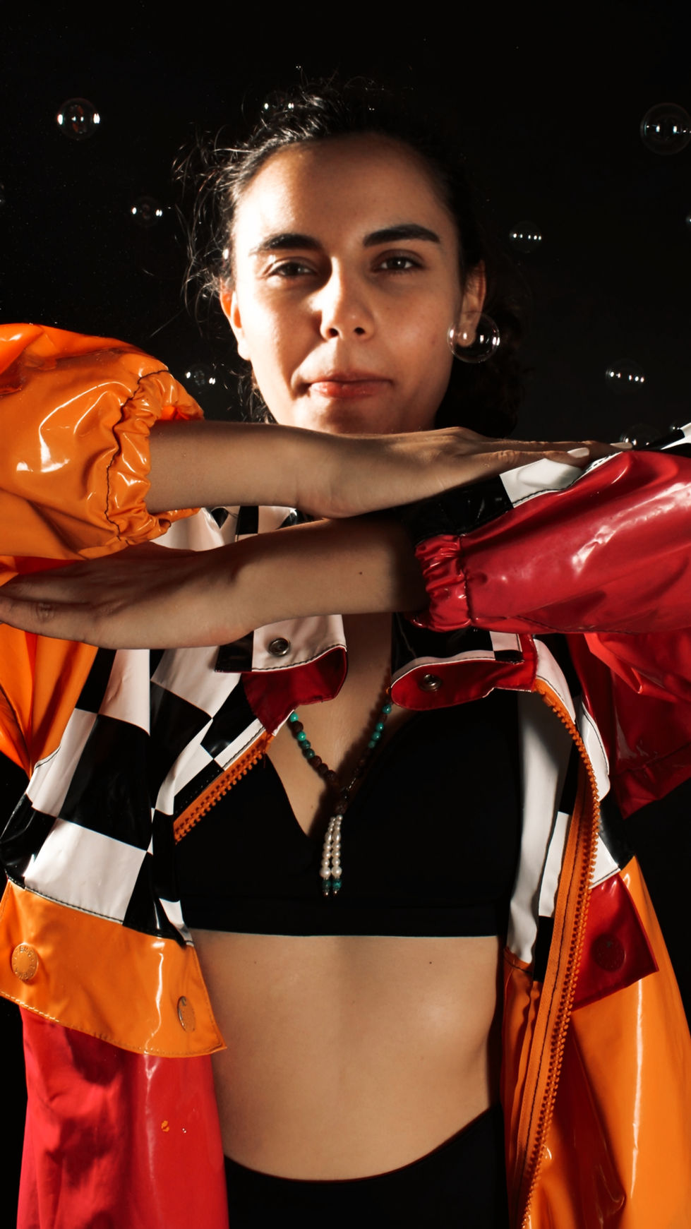 Hermosa modelo joven de cabello rubio y ojos claros realizando una pose con brazos arriba vestida con una colorida chaqueta e