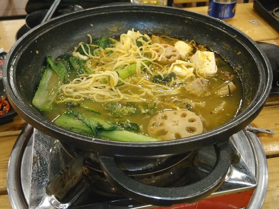 Vietnamese beef hotpot bubbling on a tabletop burner with greens, tofu and noodles