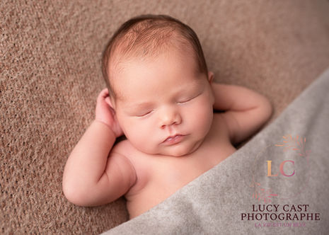 Portrait de bébé endormi dans panier vintage, mise en scène féérique avec lumières douces et couleurs chaudes, séance naissance en studio artistique près de Villefranche.