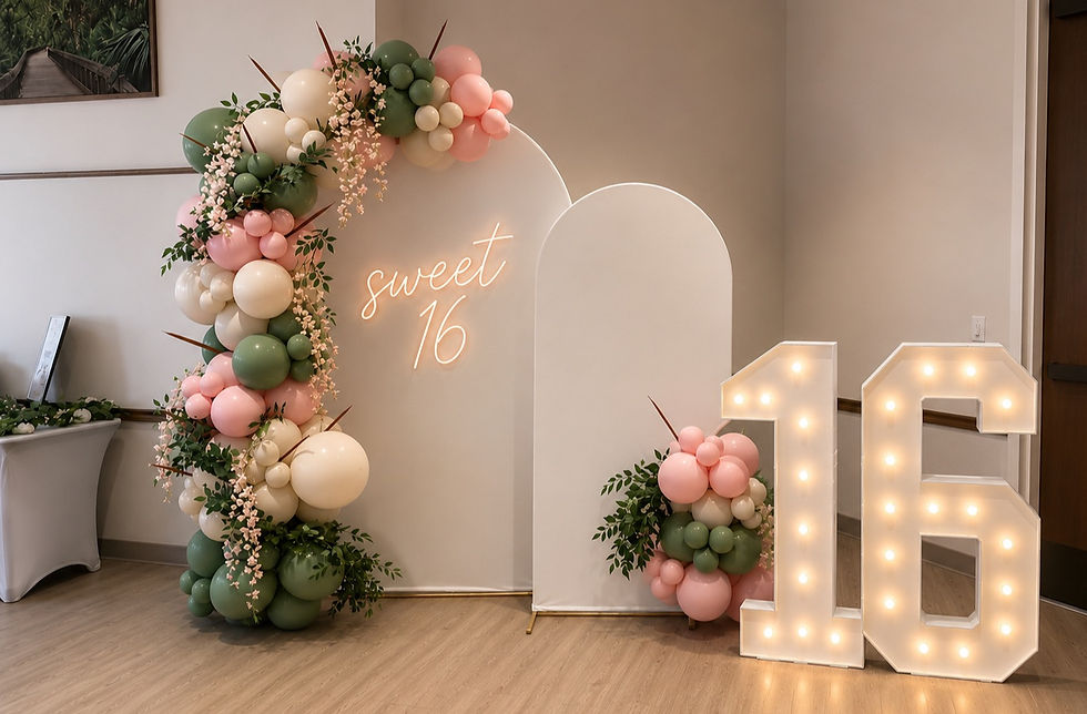 Sweet 16 party decor with custom balloon garland, modern backdrop panels, and illuminated marquee numbers creating a stylish photo backdrop.