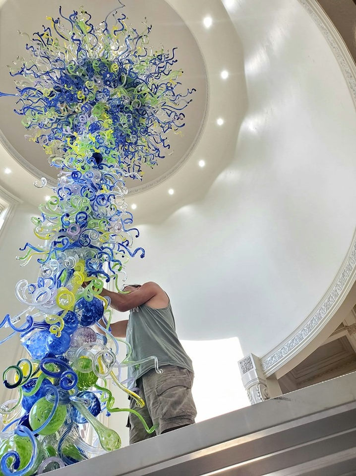 Ascension blown glass chandelier by White Elk during installation in a grand foyer