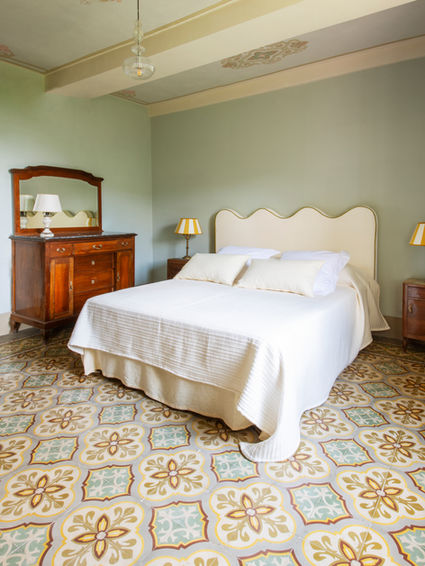 Chambre décorée en Toscane par Irène de Saint Anthost pour Irene Interiors, avec tête de lit Letti Letti et carreaux de ciment aux motifs floraux.