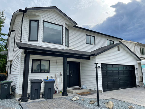 Exterior Repaint | Kelowna, BC | Exterior of a home completely repainted white with black trim and doors. Garage door was also painted black.