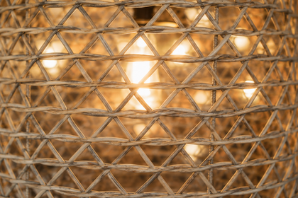Woven wicker lampshade with glowing light inside.
