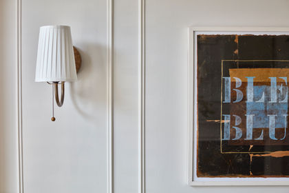 Wall sconce and framed artwork on white wall.