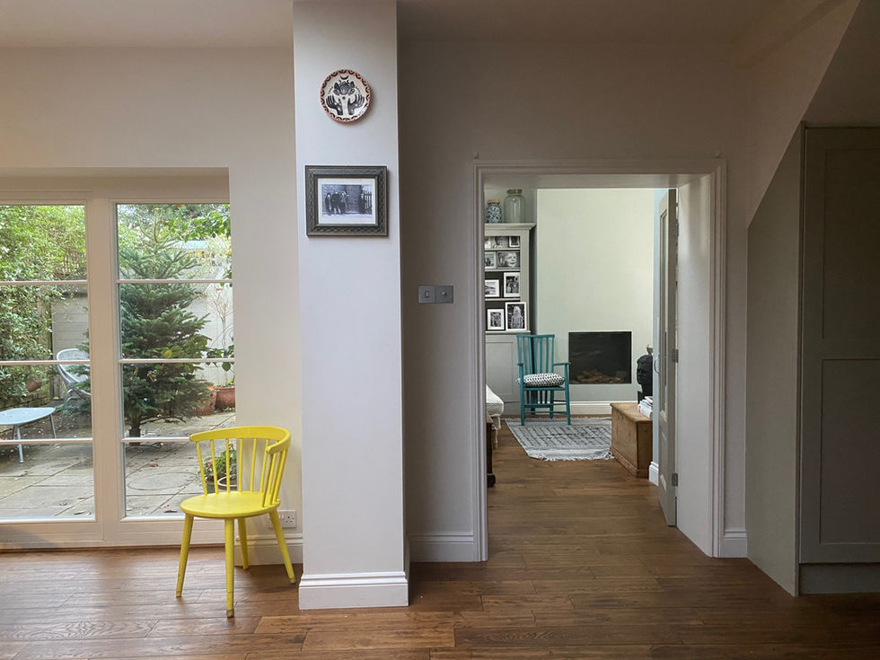 a yellow chair sits in a hallway looking into a living room