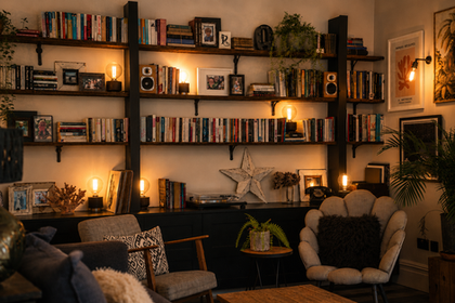 Cozy living room with bookshelves and warm lighting.