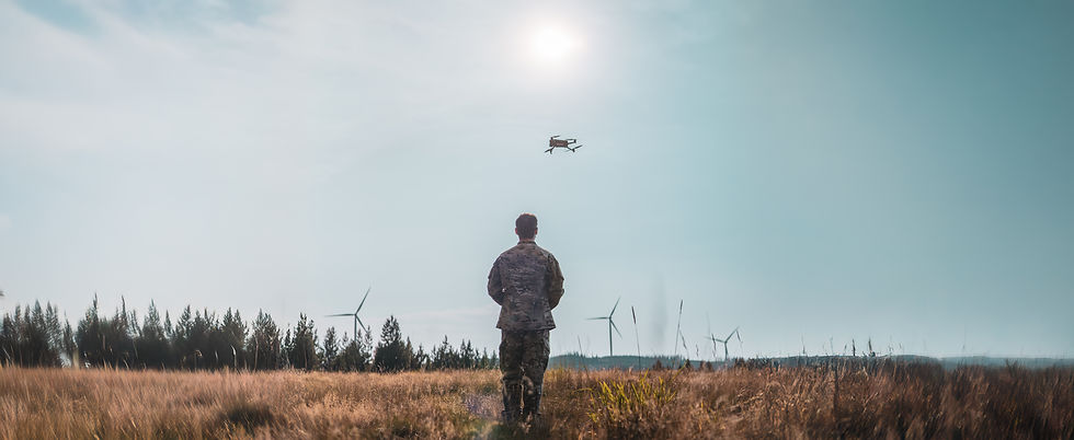 A person in camouflage military uniform controls a drone in a wheat field 