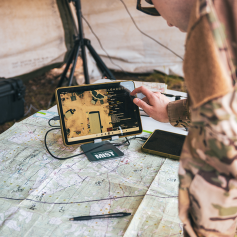 a person in military uniform leaning over a table and map to use a TerraSense MIST product on a table 