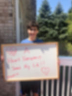 Boy holding a sign that says 'A Heart Transplant Saved my Life'