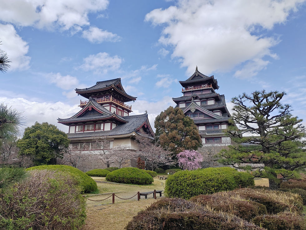Wide-angle view of the large and small concrete replica keeps of Fushimi-Momoyama Castle under a blue sky.