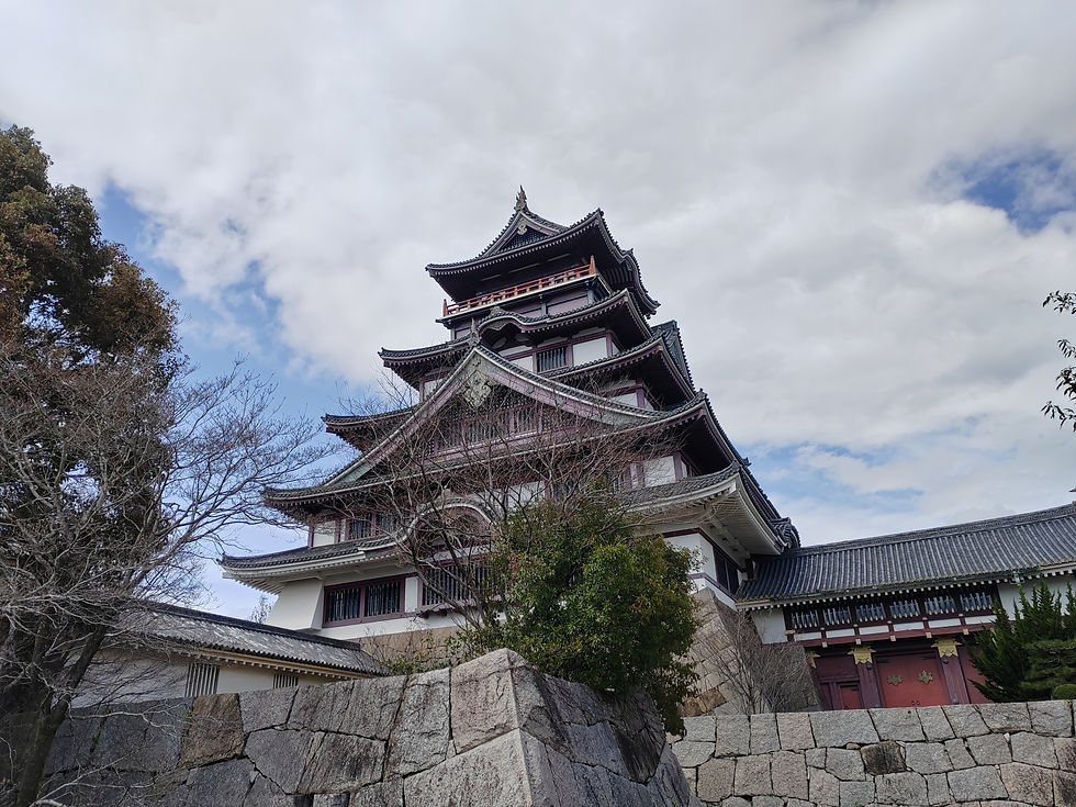 Wide-angle view of the large and small concrete replica keeps of Fushimi-Momoyama Castle under a blue sky.