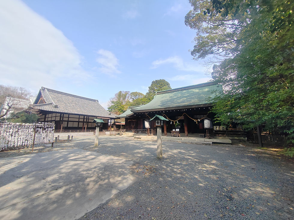 View across the gravel courtyard toward the green copper roof of the main worship hall at Minase Jingu.