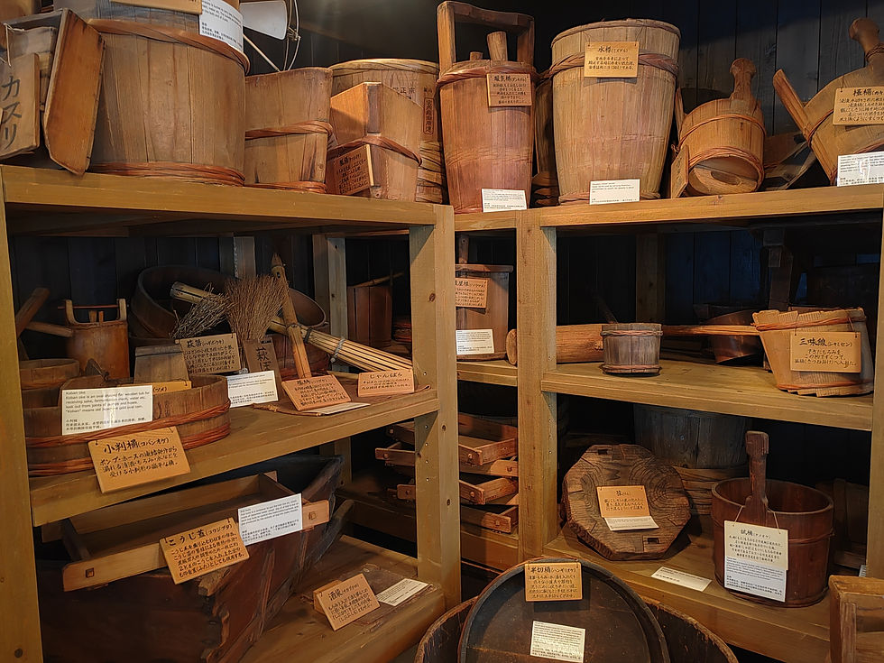 ooden shelving unit filled with traditional Japanese wooden sake buckets, scoops, and brewing utensils.