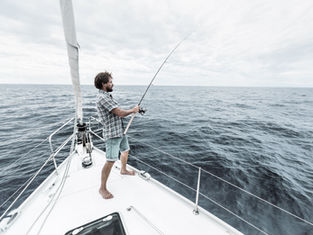 Man fishing from a sailboat on the ocean; scenic photos of Destin Florida