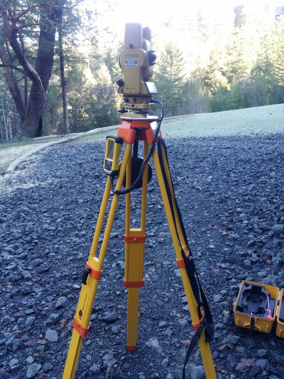 Total station set up over gravel on a wooded survey site