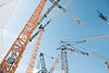 Mehrere Baukräne auf einer Großbaustelle unter klarem Himmel