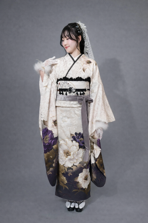 花柄のクリーム色の着物を着て、手袋と帯を締めた女性