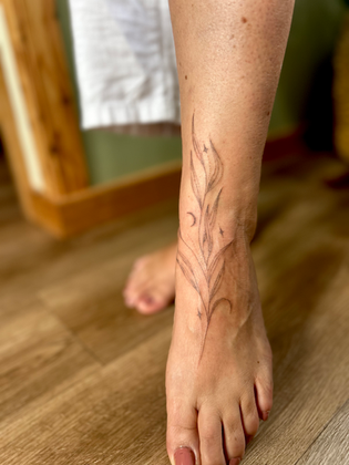 a delicate handpoked willow tattoo on a womens ankle and foot 