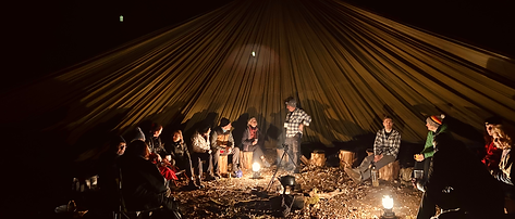Bushcraft camp lit up at night by lanterns