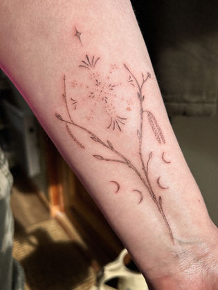 delicate hazel branch with moons and stars on a womens forearm